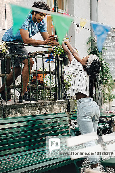 Junger Mann gibt einer Freundin während Gartenparty vom Balkon aus Essen