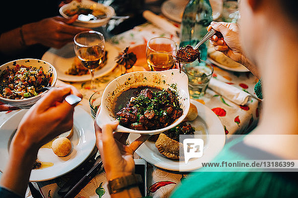 High angle view of women serving food from bowls while sitting at table in restaurant during brunch