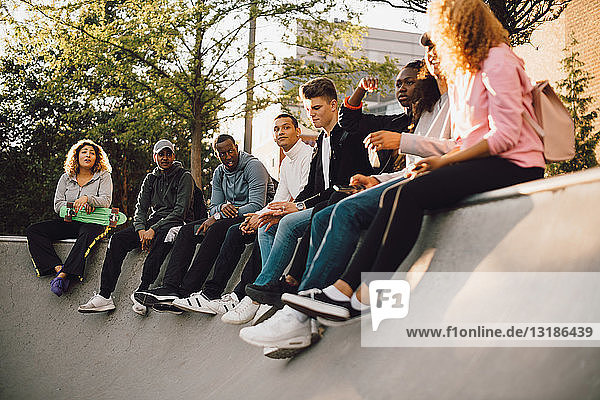 Multi-ethnische Freunde sitzen im Skateboard-Park