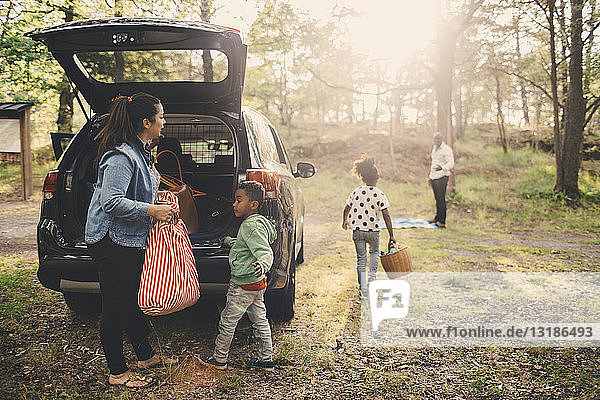 Familie entlädt Gepäck aus dem Kofferraum eines Elektroautos am Parkplatz