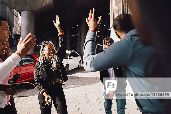 Glückliche multiethnische Freunde tanzen an sonnigen Tagen auf der Straße der Stadt