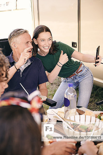 Teenagerin  die sich mit ihrem Großvater am Mobiltelefon selbstständig macht  während sie auf dem Campingplatz isst
