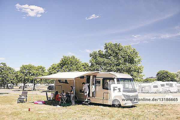 Familiencamping außerhalb des Wohnwagens auf dem Campingplatz gegen den Himmel