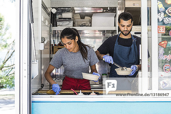 Zuversichtliche junge multi-ethnische männliche und weibliche Kollegen  die im Food Truck arbeiten