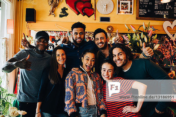 Porträt fröhlicher junger multi-ethnischer Freunde beim Stehen im Restaurant während des Brunch