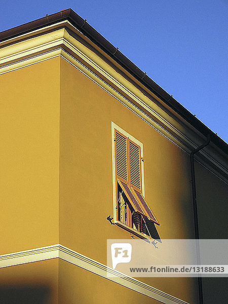 Sonnenlicht scheint auf ein gelbes Gebäude mit Fensterläden  Lerici  Ligurien  Italien