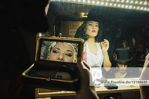 Burlesque-Darstellerinnen machen sich an Spiegeln im Umkleideraum hinter der Bühne bereit