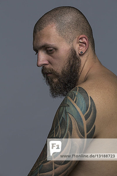 Portrait serious man with beard and tattooed arm