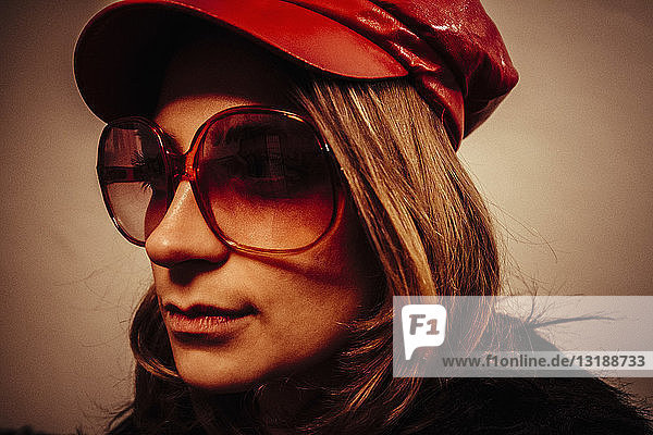Nahaufnahme Porträt kühle junge Frau trägt rote Lederkappe und Sonnenbrille