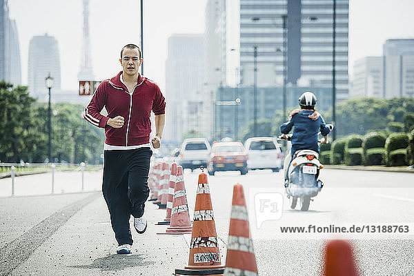 Junger Mann beim Joggen auf einer städtischen Straße,  Tokio,  Japan