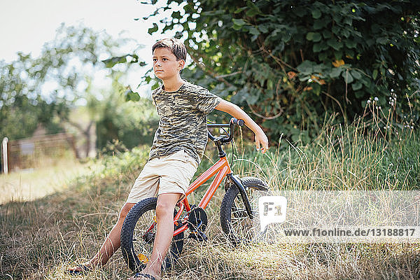 Junge mit Fahrrad im Gras