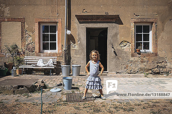 Porträt selbstbewusstes Mädchen vor sonnigem Bauernhaus stehend