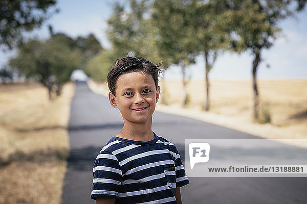 Porträt selbstbewusster Junge auf sonniger Landstraße