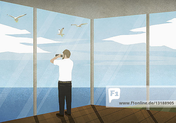 Mann mit Fernglas genießt den Meerblick vom Strandhaus aus