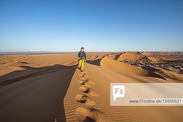 Junger Mann läuft auf Sanddüne  Erg Chebbi  Merzouga  Sahara  Marokko  Afrika