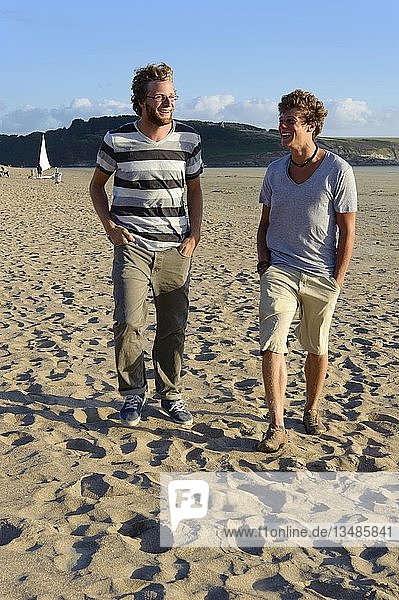 Two laughing young men are walking along the beach on the Atlantic coast  Bretagne  France  Europe