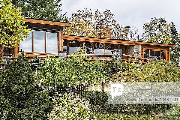 Rückansicht eines luxuriösen Hauses aus gebeiztem Zedernholz und Holz mit Panoramafenstern und Landschaftsgestaltung im Herbst  Quebec  Kanada  Nordamerika