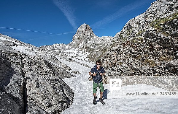 Wanderer auf Schneefeld  Wanderweg zur Wasseralm über Niederbrunnsulzen  hinter WIldalmrotenkopf  Steinernes Meer im Frühling mit Schnee  Nationalpark Berchtesgaden  Bayern  Deutschland  Europa