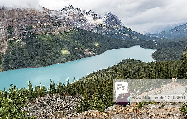 Junge Frau sitzt auf einem Stein und schaut in die Natur  türkisfarbener See  Peyto Lake  Rocky Mountains  Banff National Park  Provinz Alberta  Kanada  Nordamerika