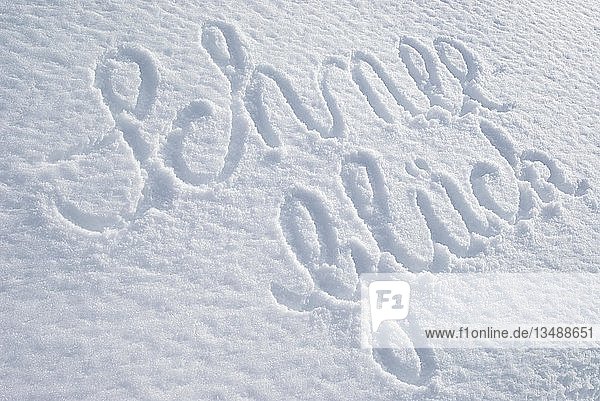 Das Wort Schnee-Glueck  geschrieben auf einer unberührten Schneedecke