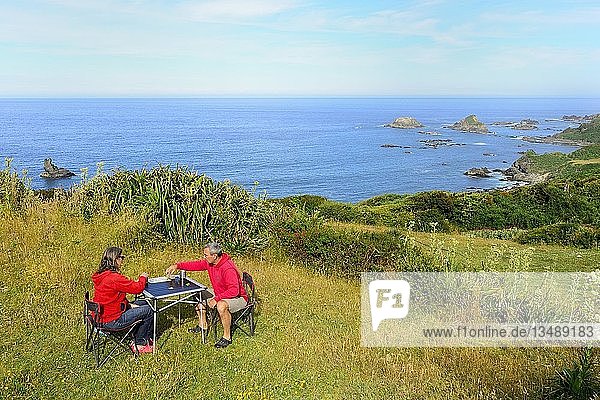 Couple plays board game on camping table  Pacific Coast  Pumillahue  Island ChiloÃ©  Chile  South America