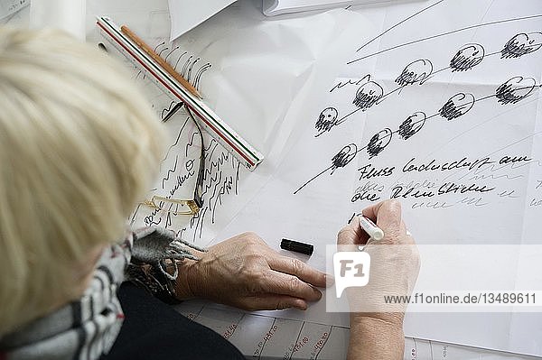 Eine Architektin sitzt am Schreibtisch in ihrem Büro und skizziert einen Plan