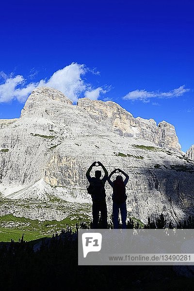 Silhouette  hikers on the hiking path 101 form a heart with their hands  behind them peaks of the Einser  Sexten Dolomites  Alta Pusteria  South Tyrol  Italy  Europe