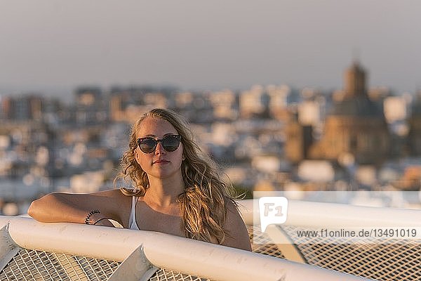 Junge Frau mit Sonnenbrille schaut in die Kamera  Plaza de la Encarnacion  hinter Häusern  Sevilla  Andalusien  Spanien  Europa