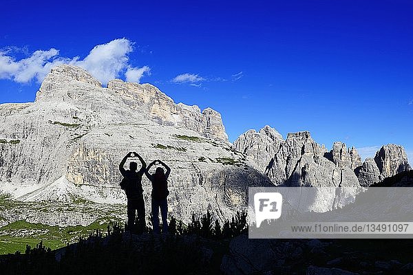 Silhouette  hikers on the hiking path 101 form a heart with their hands  behind them peaks of the Einser  Sexten Dolomites  Alta Pusteria  South Tyrol  Italy  Europe