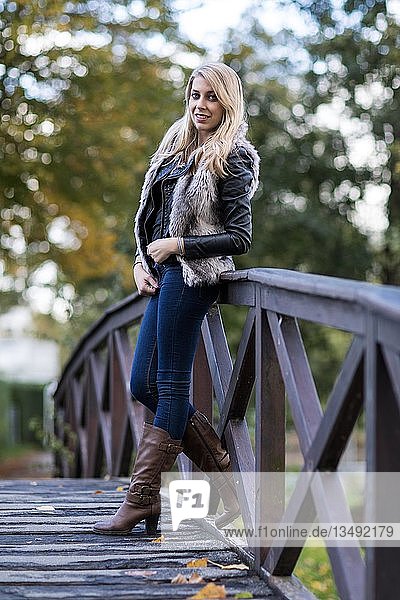 Young blonde woman poses on wooden bridge
