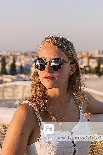 Junge Frau mit weißem Top und Sonnenbrille blickt in die Kamera Plaza de la Encarnacion hinten Häuser Sevilla Andalusien Spanien Europa