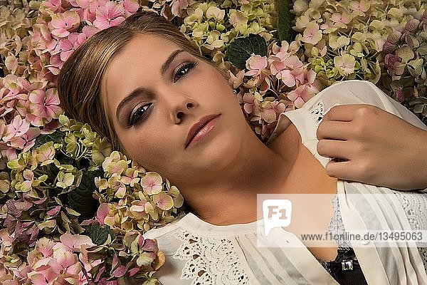 Woman lies in a sea of flowers  portrait  look into the camera