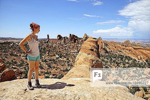 Hiker standing on Double O Arch with a view over Devil's Garden  with its sandstone formations created by erosion  Arches-Nationalpark  near Moab  Utah  United States  North America