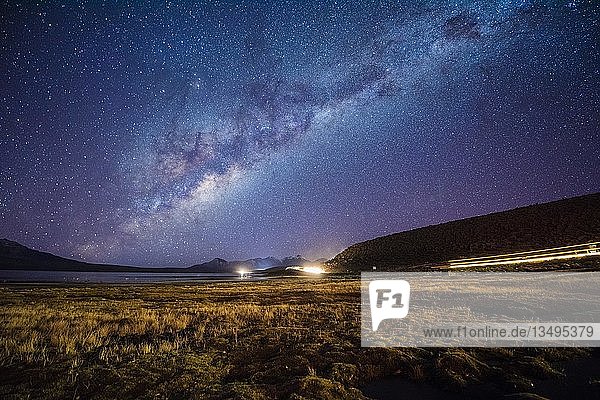 Sternenhimmel mit Milchstraße am Chungará-See  Lichtspuren von Lastwagen aus Bolivien  Nevados de Quimsachata  Lauca-Nationalpark  Putre  Provinz Parinacota  Arión y Parinacota  Chile  Südamerika