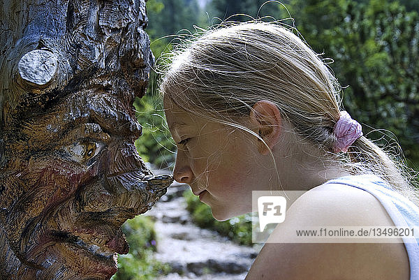 Kind vor einer Holzfigur