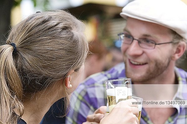 Ein junger Mann und eine junge Frau stoßen bei einer Party mit Biergläsern an  Deutschland  Europa