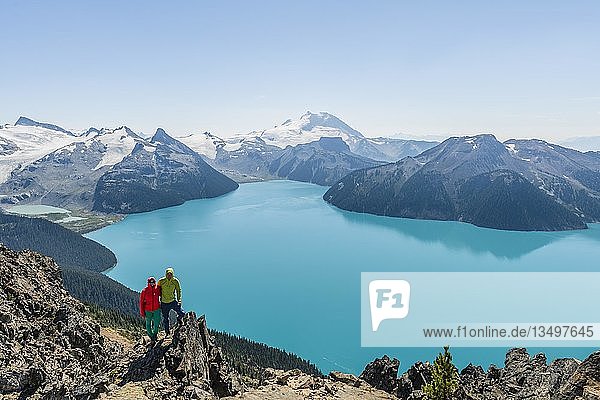 Blick vom Panorama Ridge Trail  zwei Wanderer auf einem Felsen  Garibaldi Lake  türkisfarbener Gletschersee  Guard Mountain und Deception Peak  Hintergletscher  Garibaldi Provincial Park  British Columbia  Kanada  Nordamerika