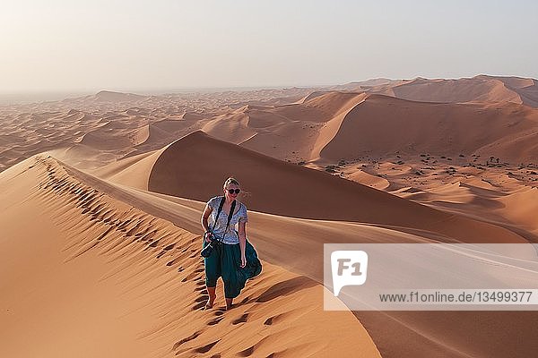 Wanderin auf einer roten Sanddüne in der Wüste  Dünenlandschaft Erg Chebbi  Merzouga  Sahara  Marokko  Afrika