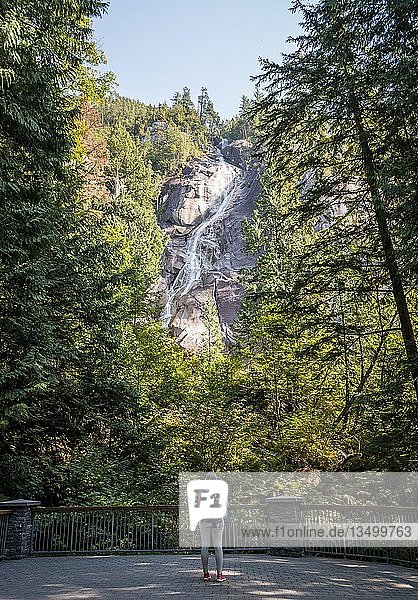 Junge Frau steht vor Shannon Falls  Wasserfall an steilem Felsen  British Columbia  Kanada  Nordamerika