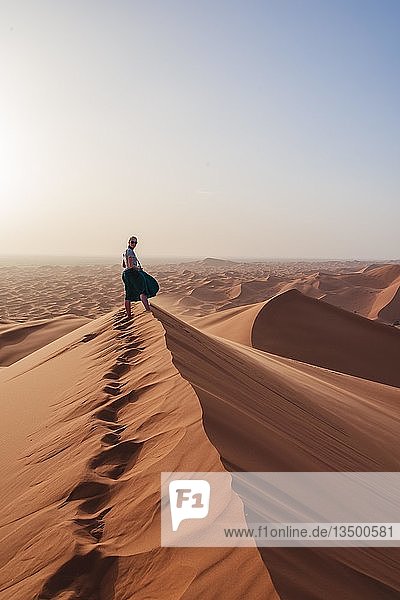 Wanderin auf einer roten Sanddüne in der Wüste Dünenlandschaft Erg Chebbi Merzouga Sahara Marokko Afrika