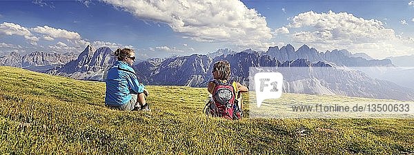 Hikers sitting on the Aferer Alm alp on Plosen mountain  enjoying the view of the Afer Geisler group and Peitlerkofel mountain  Wuerzjoch ridge  Villnoesstal valley  Dolomites  province of Bolzano-Bozen  Italy  Europe