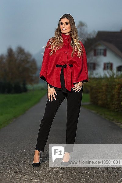 Young woman with red top and black trousers at the blue hour
