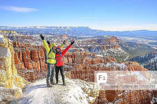 Touristen mit ausgestreckten Armen vor dem Amphitheater  bizarre schneebedeckte Felslandschaft mit Hoodoos im Winter  Rim Trail  Bryce Canyon National Park  Utah  USA  Nordamerika
