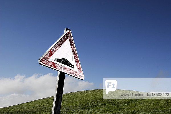 Straßenschild  das vor einer holprigen Straße warnt  vor einem grünen Hügel unter einem blauen Himmel  Campo Imperatore  Abruzzen  Italien  Europa