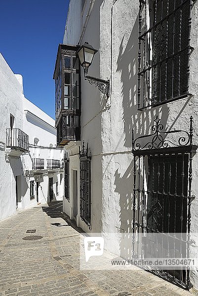 Gasse und strahlend weiß getünchte  mit Gittern versehene Häuser in der auf einem Hügel gelegenen Stadt Vejer de la Frontera  Provinz Cádiz  Andalusien  Spanien  Europa