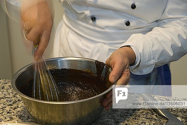 Cooking course  creation of a light-dark chocolate tarte  hands whipping the mass in the pot on the stove  Germany  Europe