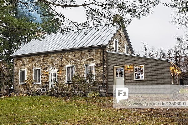Alte Hausfassade im Landhausstil von 1820 aus behauenen Steinen und Feldsteinen mit Zedernschindeln als Anbau im Herbst  Quebec  Kanada  Nordamerika