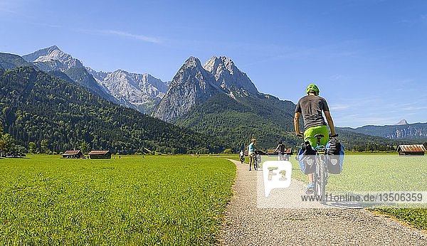 Cyclist on bike tour riding on bike path on his mountain bike  in the back Zugspitze  Tegernauweg  near Grainau  crossing the Alps  Garmisch-Partenkirchen  Upper Bavaria  Bavaria  Germany  Europe