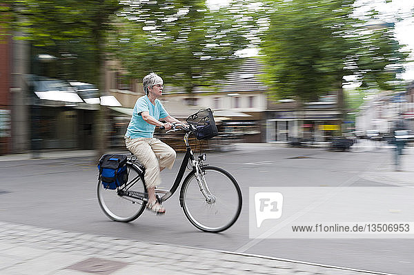 Frau fährt mit ihrem Fahrrad über den Marktplatz  Grevenbroich  Nordrhein-Westfalen  Deutschland  Europa