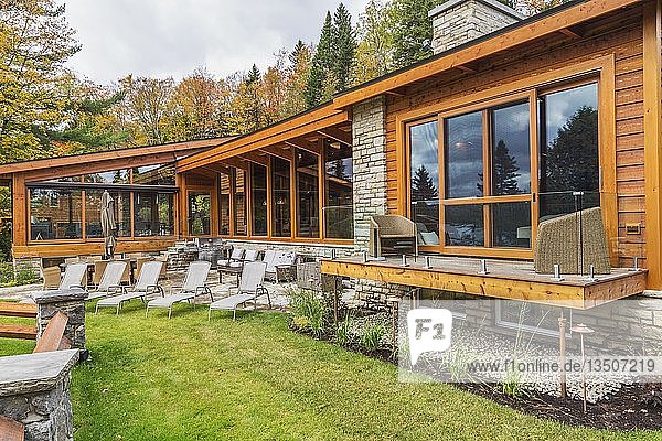 Rückansicht eines luxuriösen Hauses aus gebeiztem Zedernholz und Holz mit Panoramafenstern  Terrasse und Natursteinterrasse im Herbst  Quebec  Kanada  Nordamerika